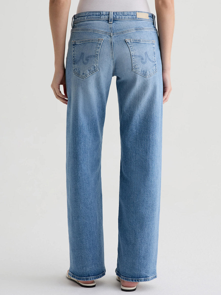 Person wearing AG Jeans Adria Twisted Leg Low-Rise Wide Leg in Helios, made from Italian denim, shown from the back against a plain light background.