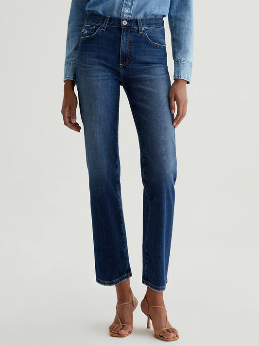 Person wearing a denim shirt, AG Jeans Brinley Crop in 7 Years La Jolla, and tan heeled sandals stands against a plain background.