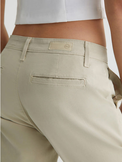 Close-up of a person wearing AG Jeans Caden in Cream Froth with back pockets and a focus on the stitching details.