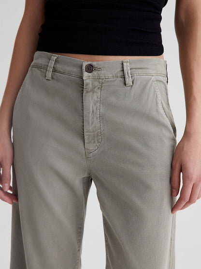 Close-up of a person wearing AG Jeans Caden in Dried Parsley with a black top cropped at the waist.