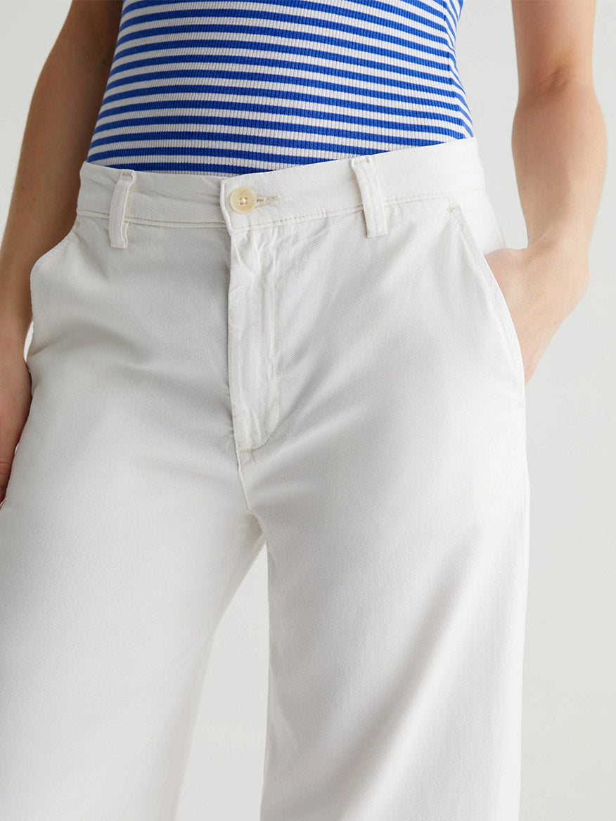 The individual sports a blue and white striped top with AG Jeans Caden Wide-Leg Trouser in Powder, hands casually tucked into pockets, set against a plain background.