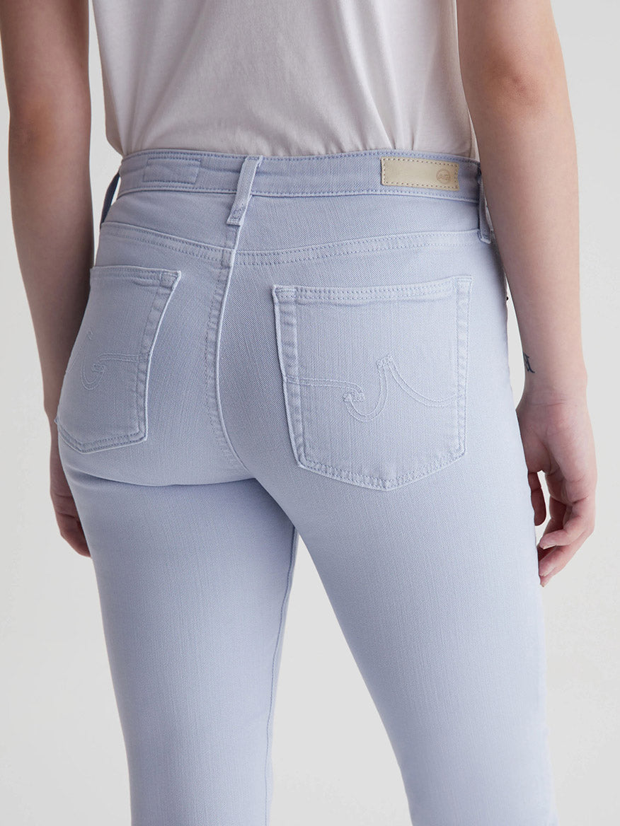 Person wearing light-colored AG Jeans Prima Cigarette Leg in Sulfur Blue Whisper with a visible back pocket design.