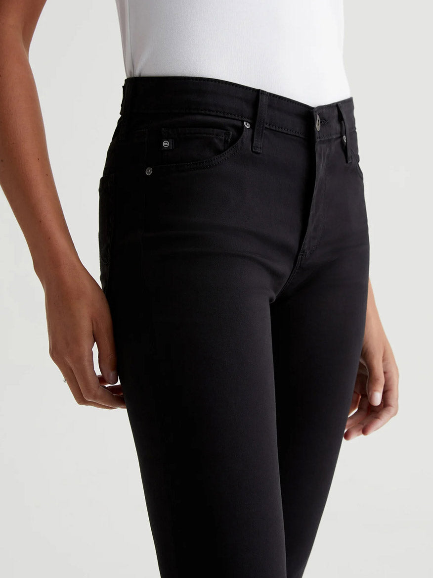 The back view of a woman wearing AG Jeans Prima Cigarette Leg in Super Black with a deep black hue.
