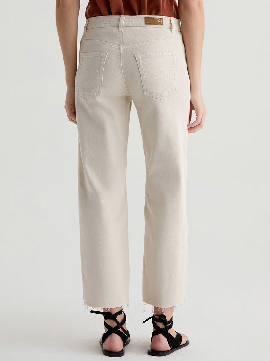 Person wearing AG Jeans Saige Wide Leg Crop With Panel in Opal Stone and black sandals, photographed from the back against a plain light background.