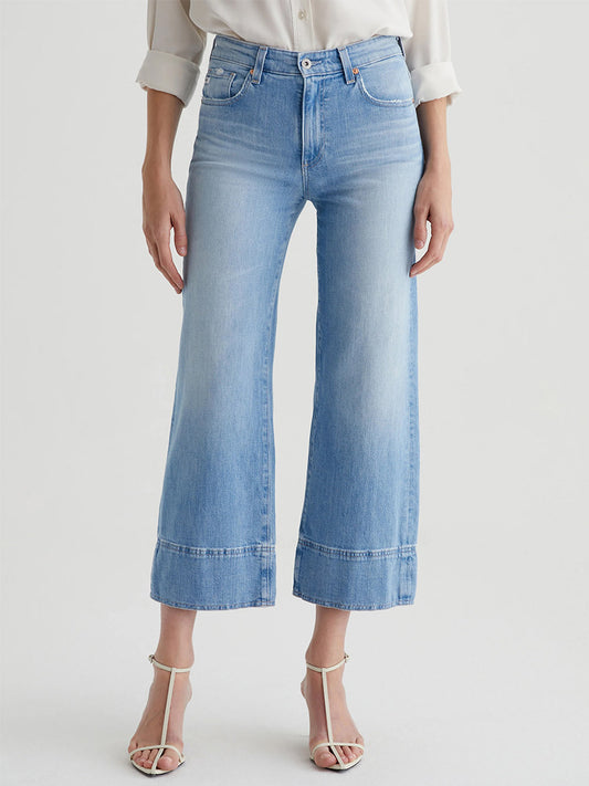 Person wearing AG Jeans Saige Wide Leg Crop in Dana Point with white heeled sandals, shown from shoulders down against a plain background.