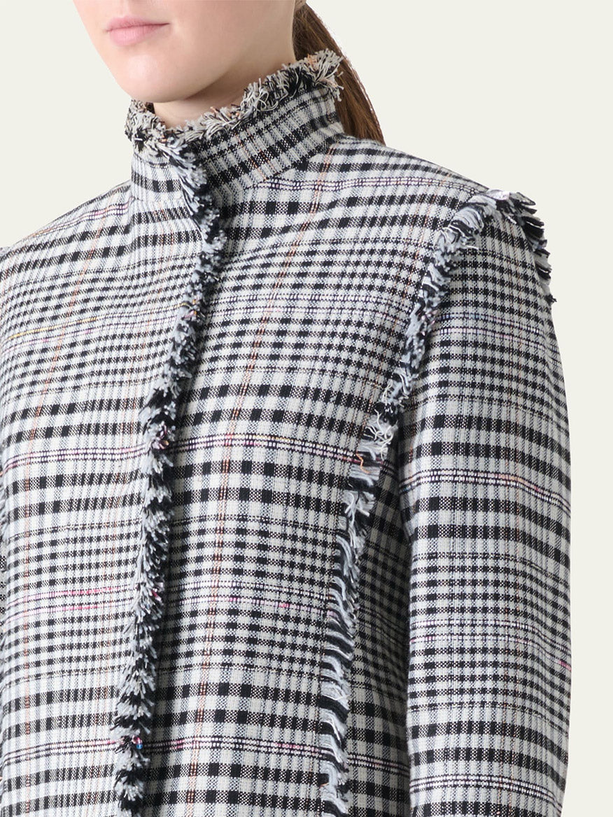 A person wearing the Akris Punto Check Fringe Hem Cropped Jacket in Cream/Black, a high-neck, long-sleeve plaid piece with raw fringed edges and a boxy silhouette.