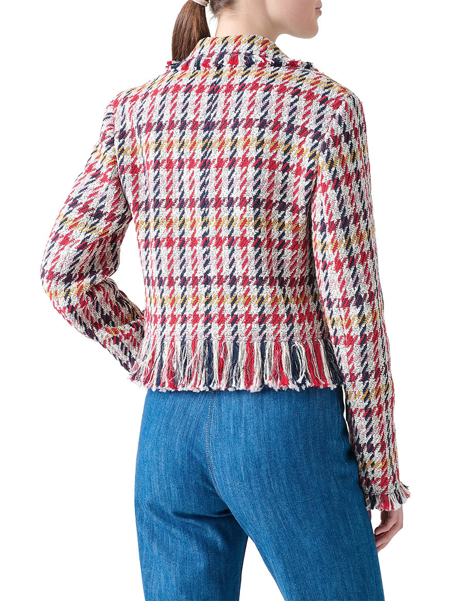 A woman with a ponytail is seen from the back wearing an Akris Punto Houndstooth Tweed Fringe Trim Blazer in Cream Multi and blue jeans, set against a white background.