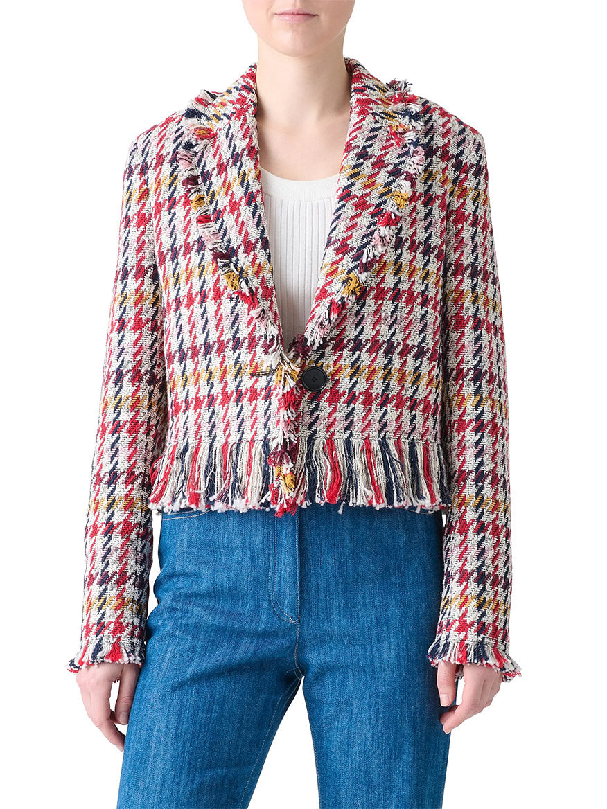 A person wearing the Akris Punto Houndstooth Tweed Fringe Trim Blazer in Cream Multi over a white top and blue jeans.