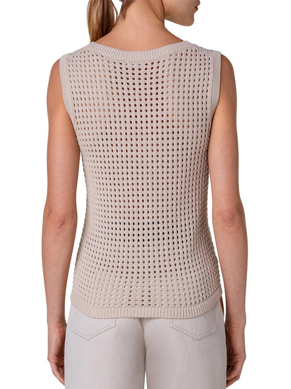 The woman is wearing a beige knit sweater with an open mesh stitch, giving it an Akris Punto Chunky Mesh Scoop Neck Tank in Cashew aesthetic.