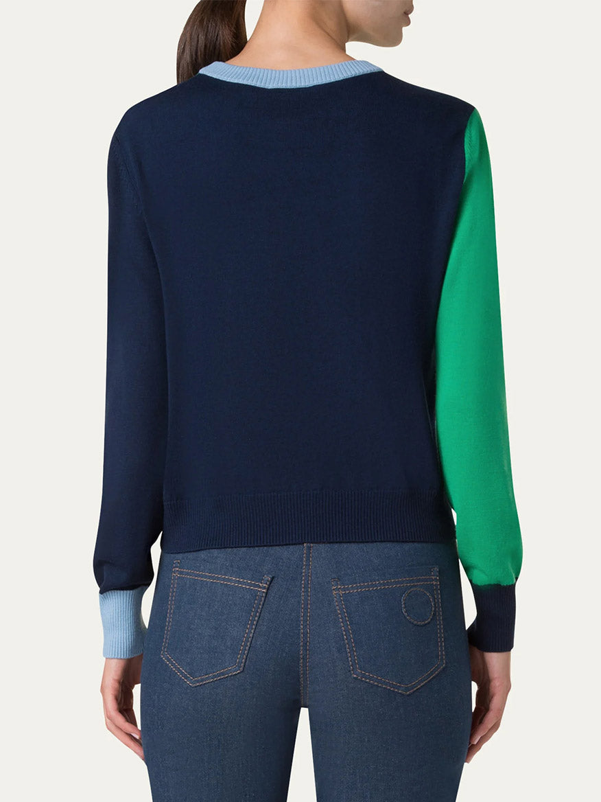 A person in an Akris Punto Colorblock Merino Sweater in Sea Green/Navy/Sky, crafted from wool yarn for a relaxed fit, with blue jeans, viewed from the back.