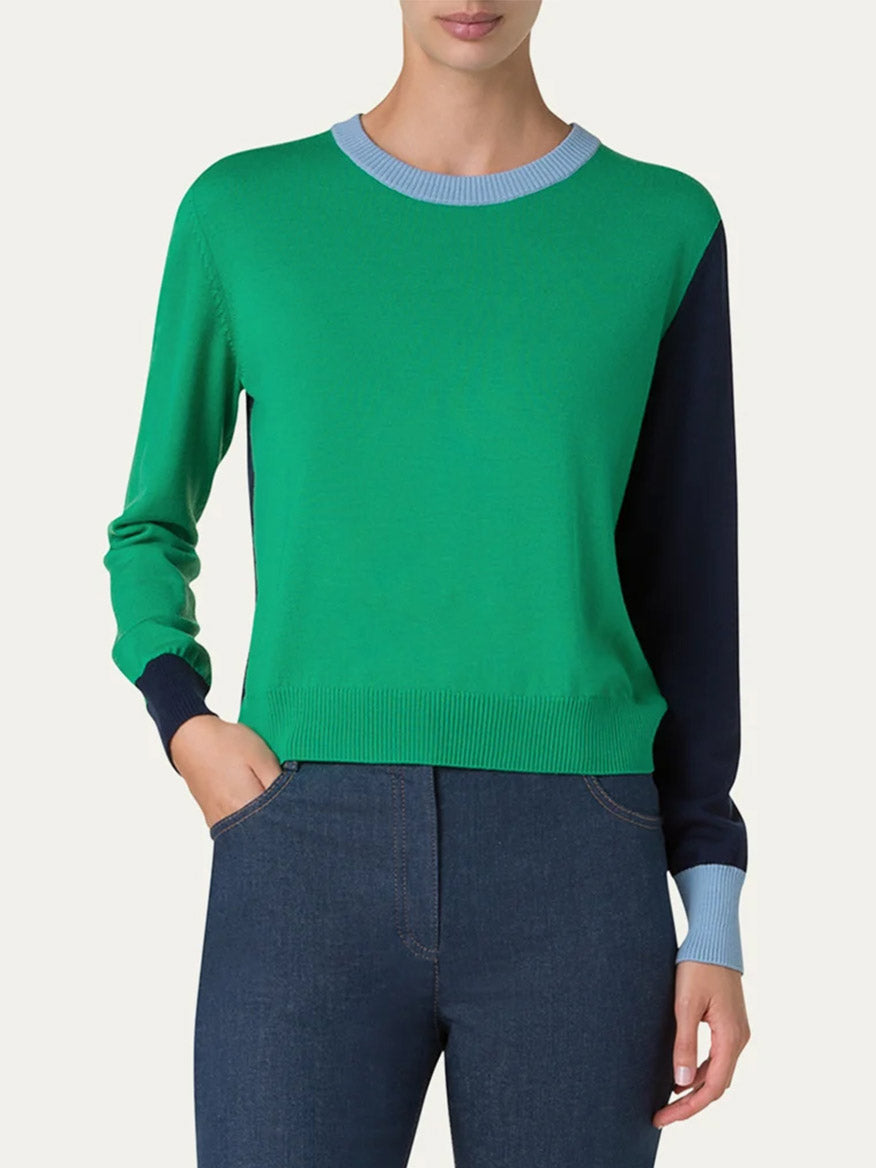 The person is in a relaxed fit, wearing an Akris Punto Colorblock Merino Sweater in Sea Green/Navy/Sky, paired with dark jeans.