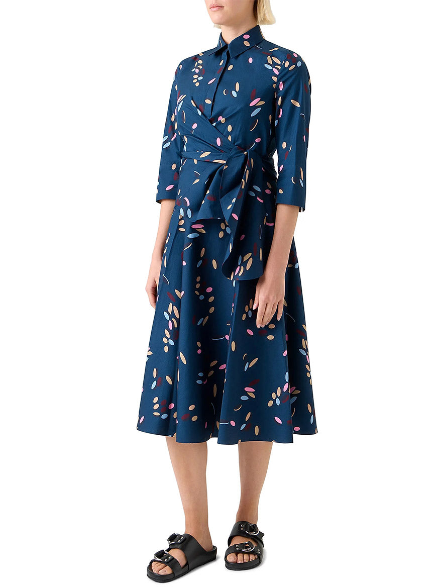 A person wearing the Akris Punto Confetti Print Wrap Dress in Ink Multi with 3/4 sleeves and black sandals stands against a white background.