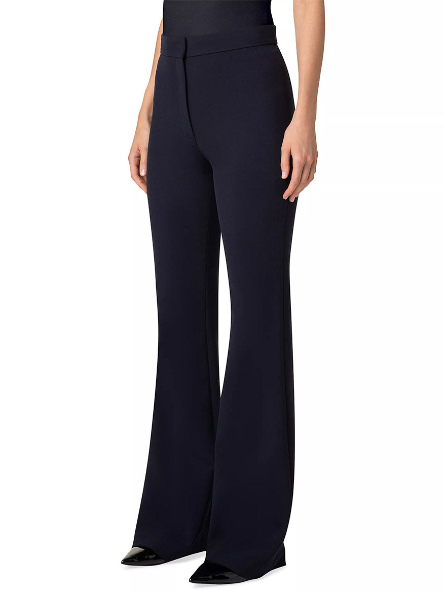 A person wearing Akris Punto Courtney Crepe Boot-Cut Pants in navy enjoys a fitted waist and sleek silhouette. Crafted from stretchy pebble crepe, these high-waisted pants offer an elegant, leg-lengthening effect to any ensemble.