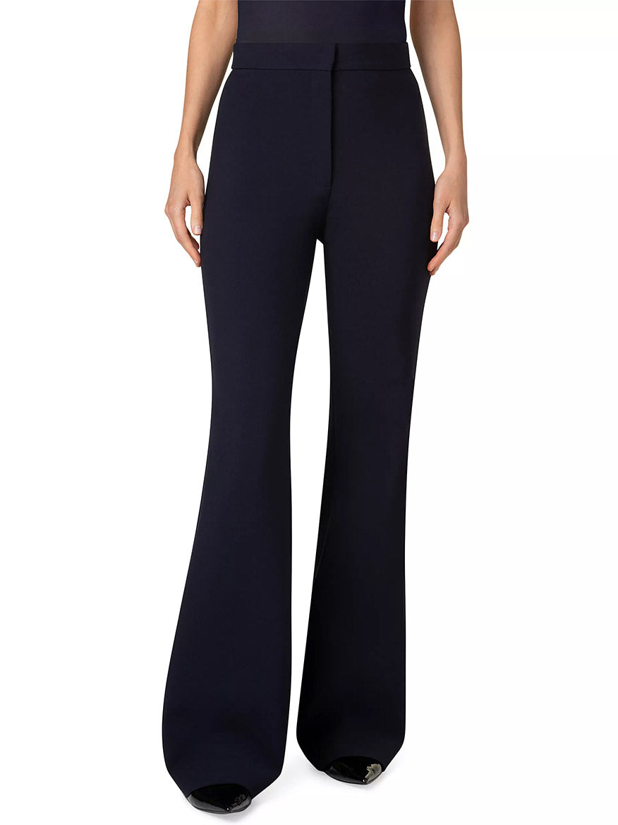The individual dons Akris Punto Courtney Crepe Boot-Cut Pants in navy, featuring a high waist and stretchy pebble crepe fabric that enhances leg length. The image focuses on the fit from waist to feet against a plain backdrop.