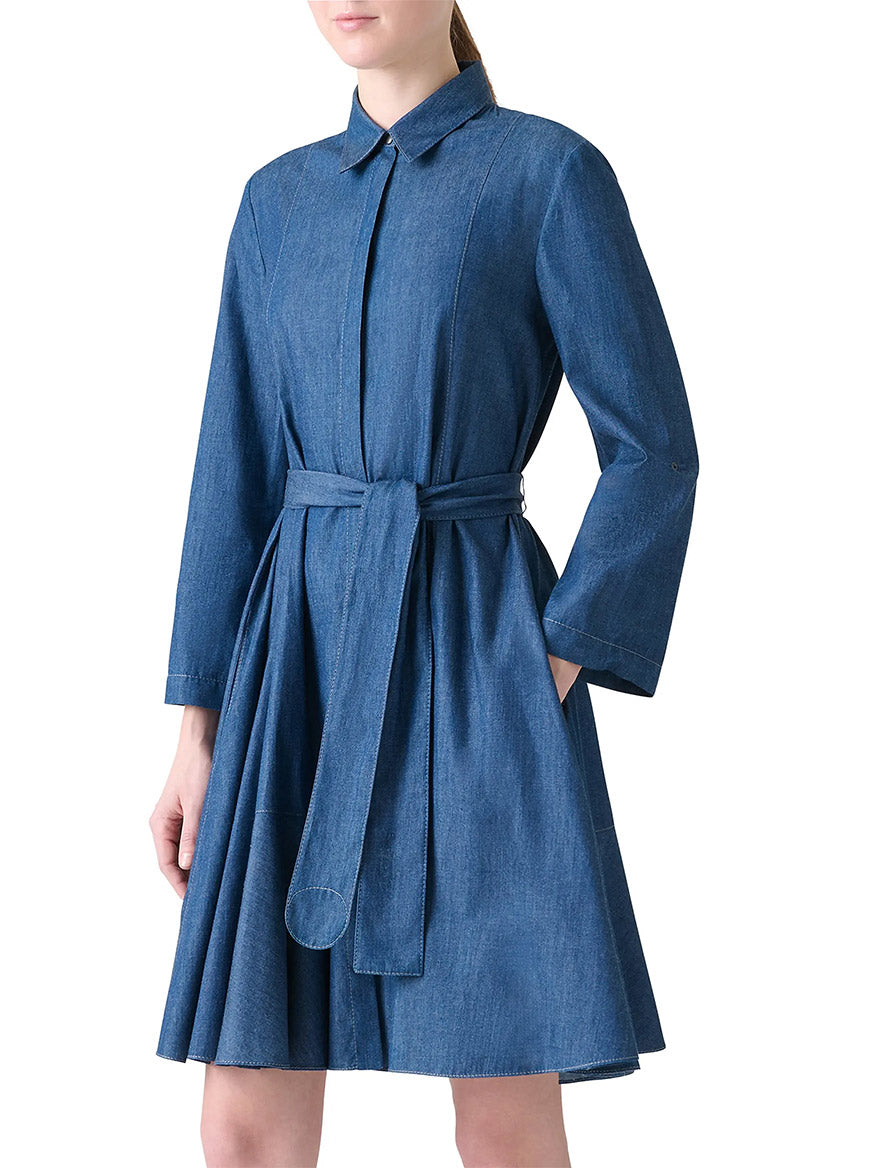Woman in the Akris Punto Tie-Waist Denim Shirtdress in Medium Blue, featuring long sleeves, a collar, belt at the waist, A-line silhouette, flared skirt, and pockets.