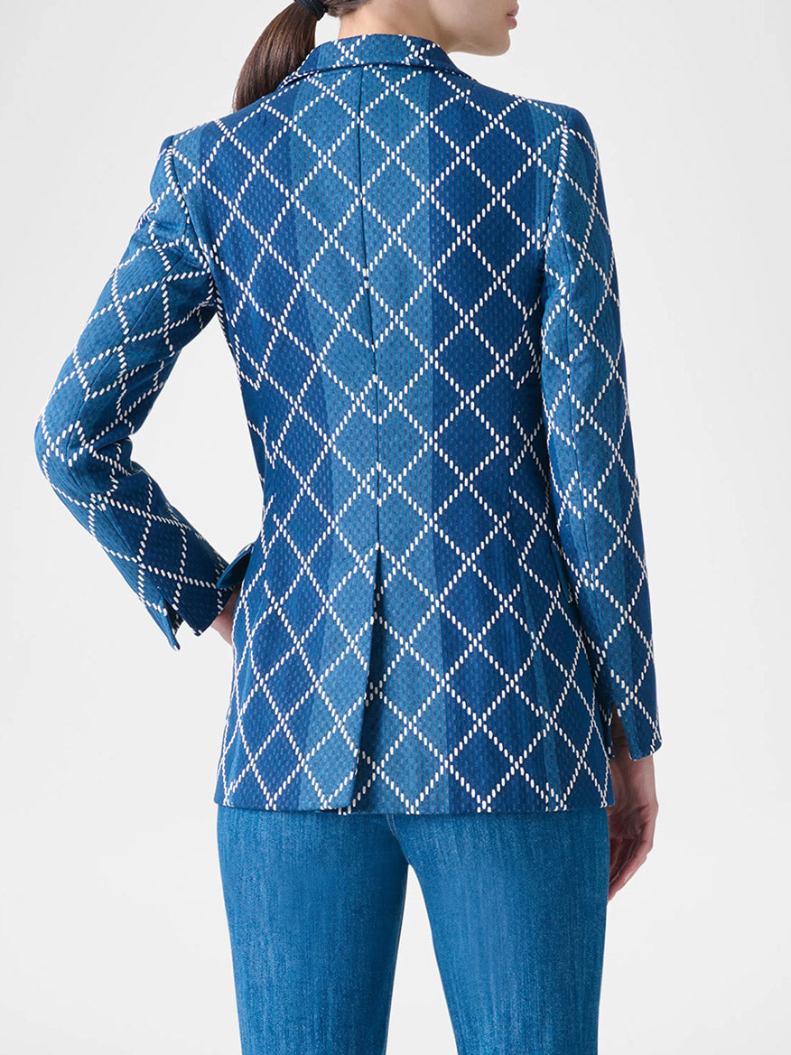 Person seen from behind wearing the Akris Punto Diamond Cotton Jacquard Fitted Blazer in Medium Blue Multi with blue jeans, against a plain light background.