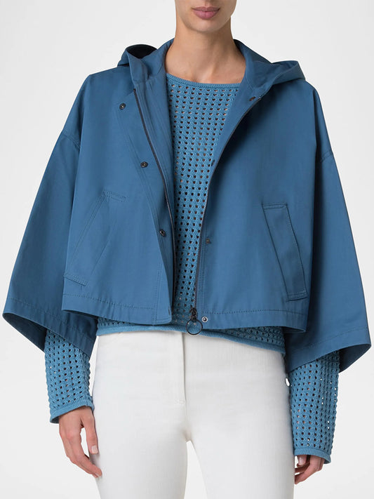 A person wearing the Akris Punto Cotton Gabardine Carcoat in Medium Blue over a textured blue sweater and white pants, photographed from the front.