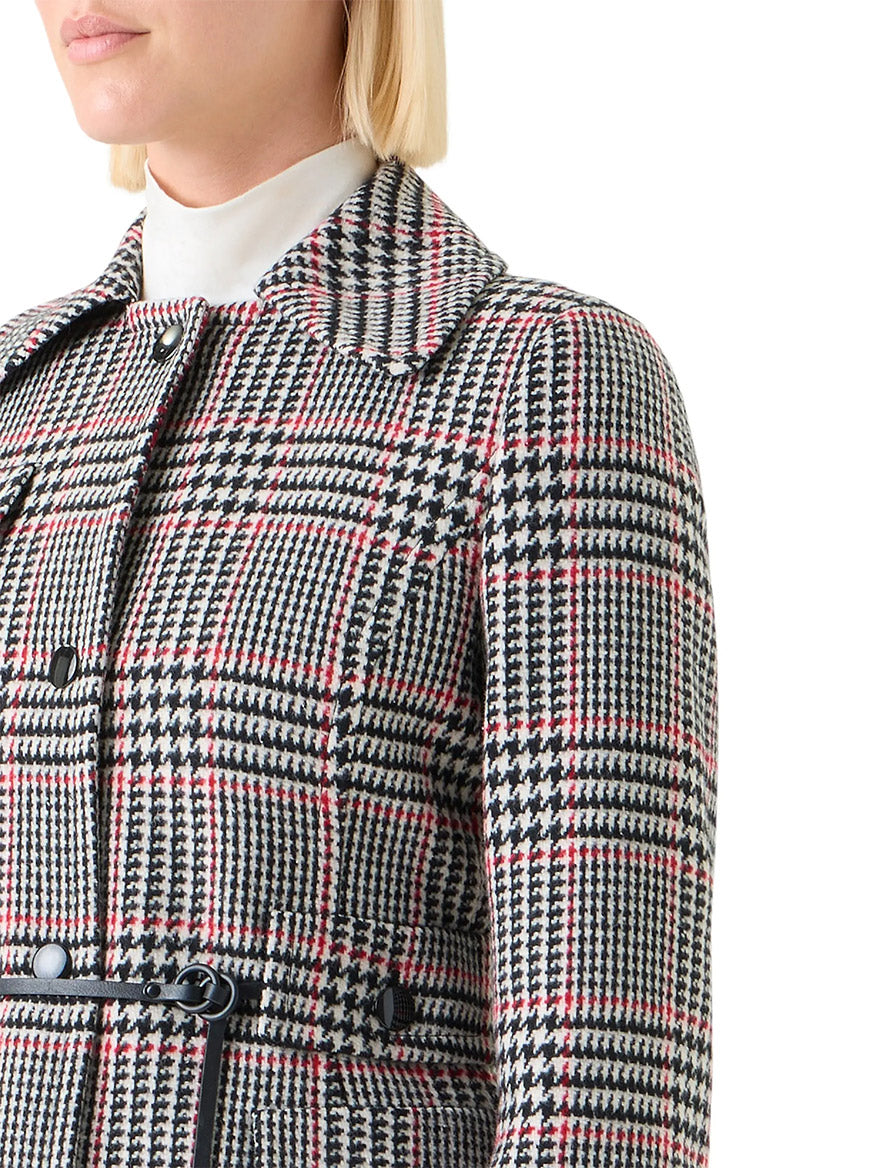 A person with short blonde hair wears the Akris Punto Glencheck Wool-Blend Jacket in Black/Cream/Vermillion over a white turtleneck, styled with a leather belt.