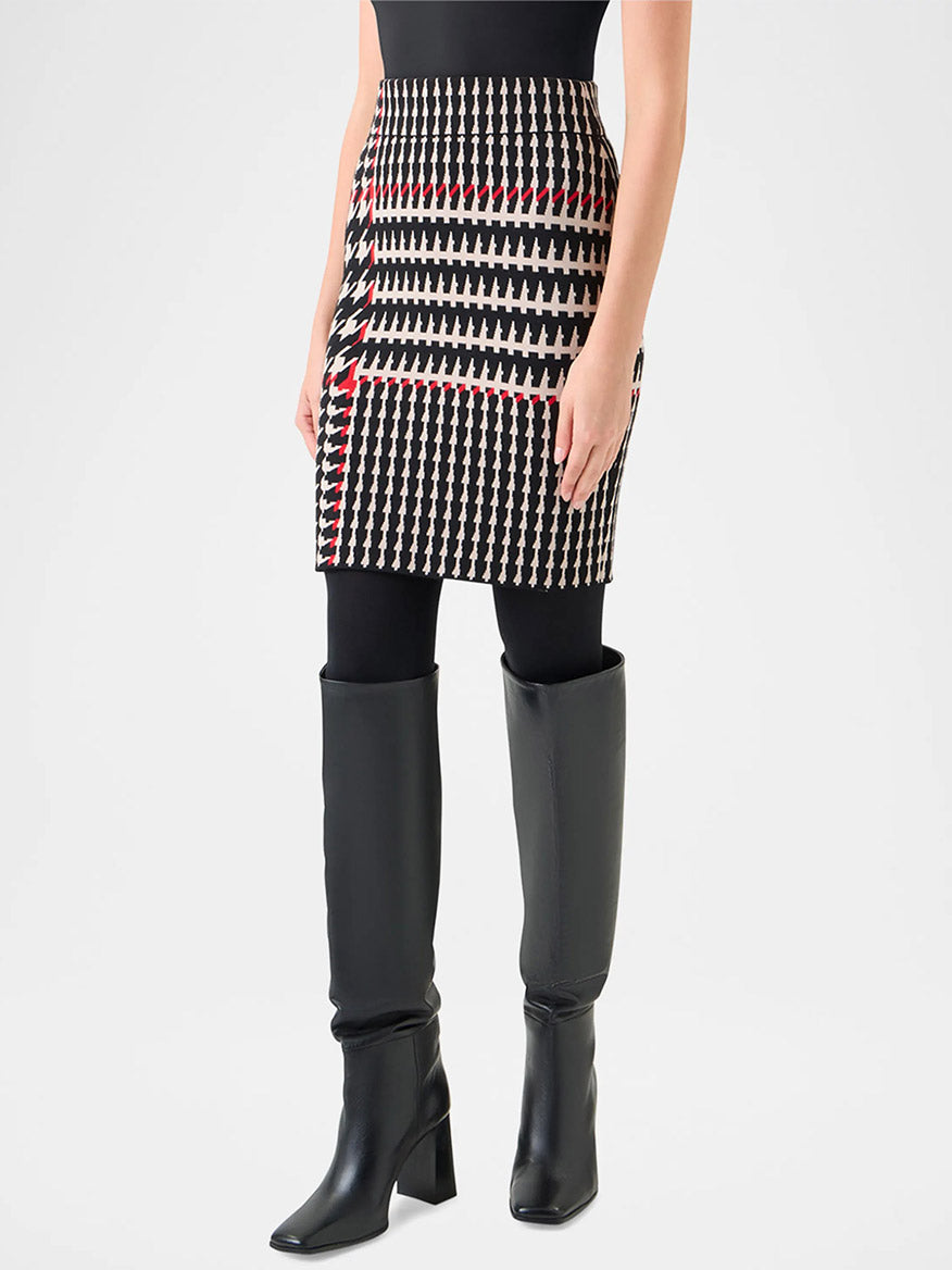 Person wearing a black sleeveless top, black tights, knee-high black boots, and the Akris Punto Fitted Wool-Blend Plaid Jacquard Skirt in Black/Cream/Vermillion.