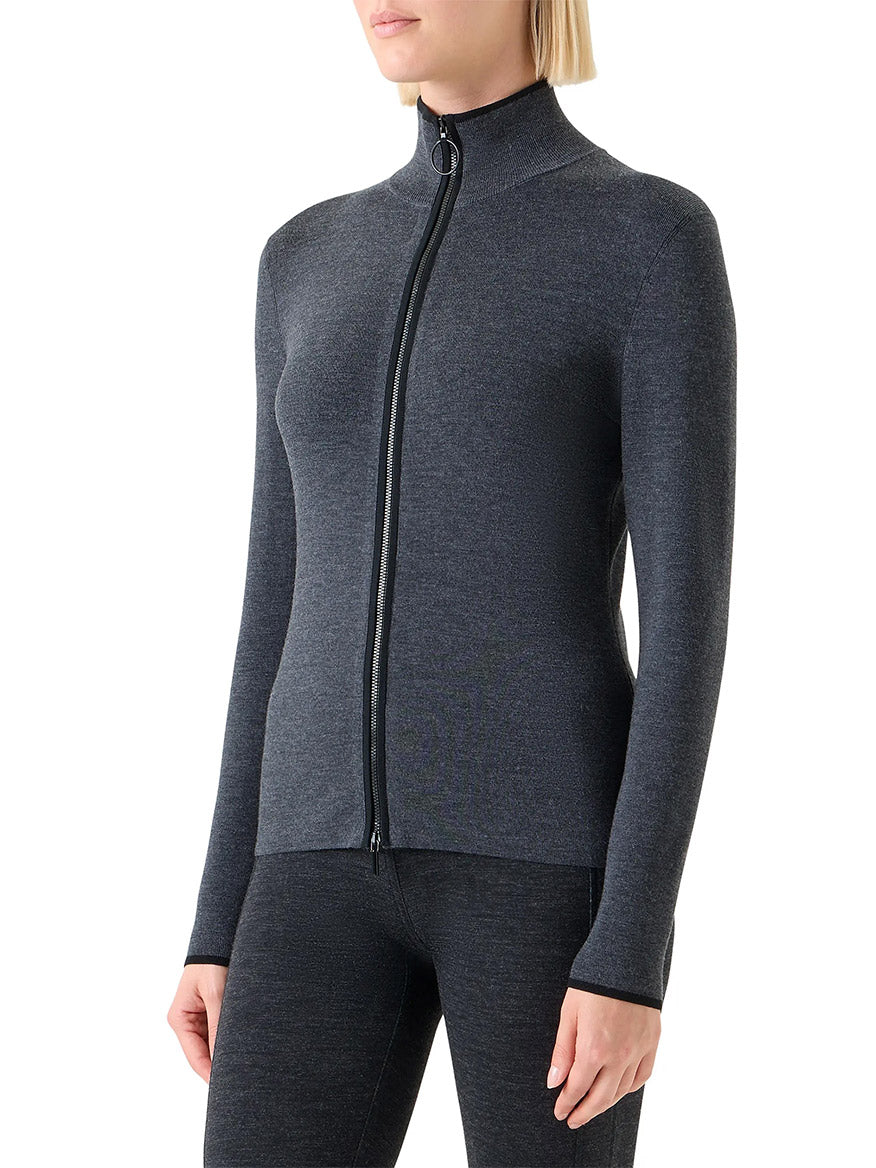 A person wearing a fitted, long-sleeve Akris Punto Virgin Wool Knit Zip Cardigan in Charcoal/Black, with matching leggings, stands with arms relaxed at their sides.