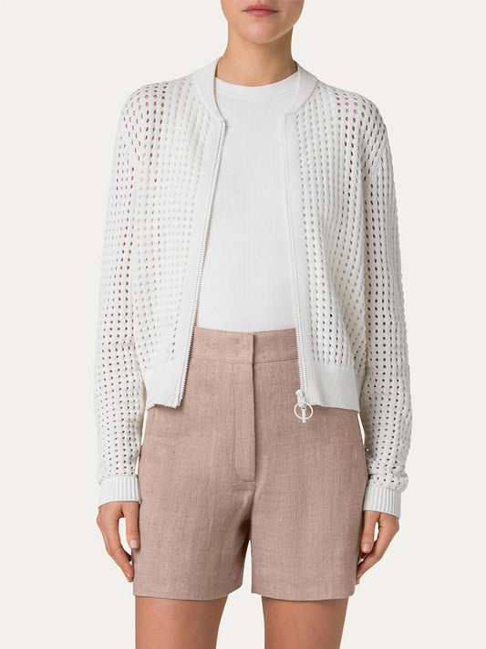 A woman wears the Akris Punto Chunky Mesh Bomber Cardigan in Cream over a white top and high-waisted beige shorts, standing against a plain background.