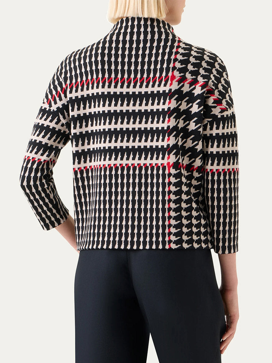 A person is seen from the back wearing the Akris Punto Mock Neck Plaid Sweater in Black/Cream/Vermillion, featuring three-quarter sleeves, paired with black pants.