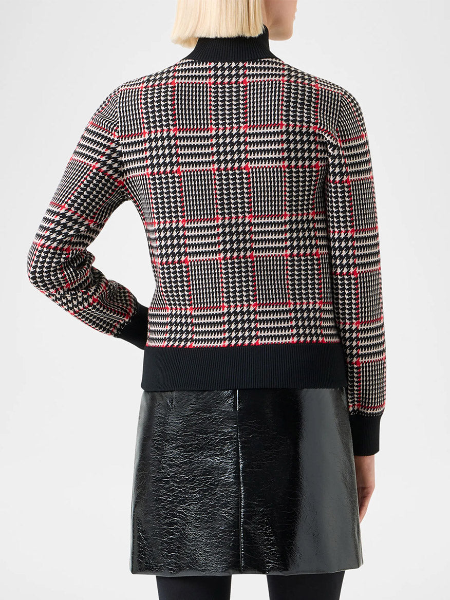 A person with blonde hair is shown from the back, wearing the Akris Punto Mock Neck Plaid Cardigan in Black/Cream/Vermillion and a shiny black skirt.