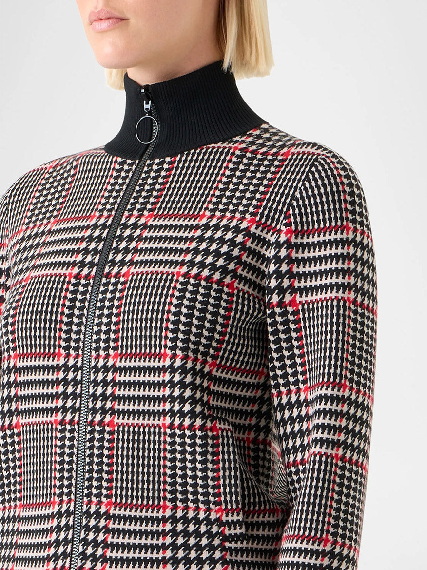A person with short blond hair wears the Akris Punto Mock Neck Plaid Cardigan in Black/Cream/Vermillion, a slim fit zip-up style featuring a jacquard plaid pattern and a black ribbed collar.