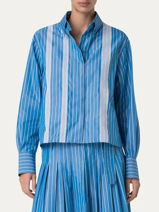Wearing the Akris Punto Pajama Stripe Boxy Collared Shirt in Medium Blue/Cream, a person stands against a plain background paired with a matching pleated skirt.