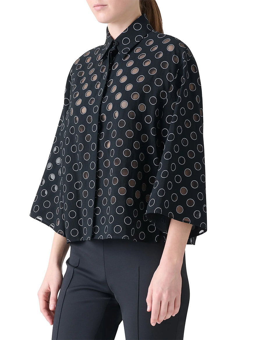 A person models the Akris Punto Boxy Polka Dot Organzino Blouse in Black/Cream with black pants, shown from the waist up against a white background.