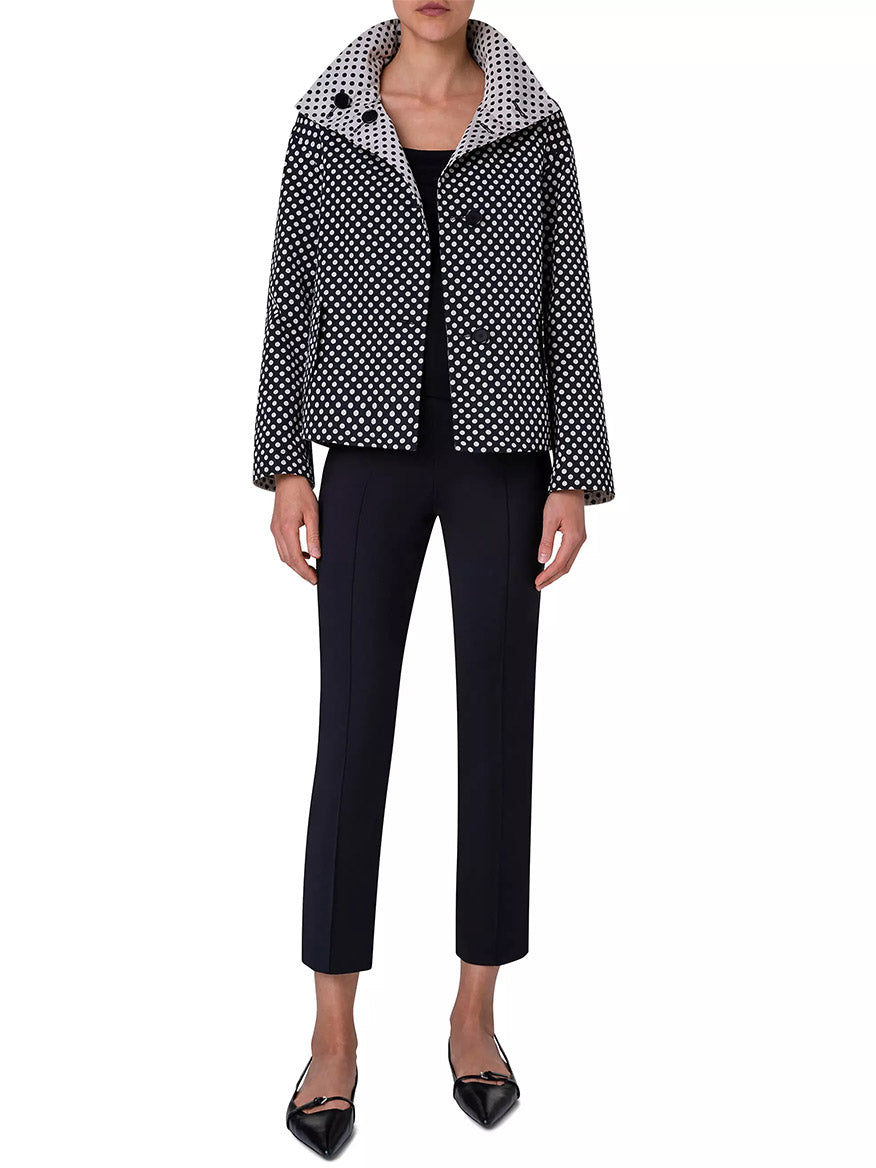 A person wearing the Akris Punto Reversible Polka Dot Jacket in Black/Navy over a black top, black ankle-length pants, and black pointed-toe shoes.