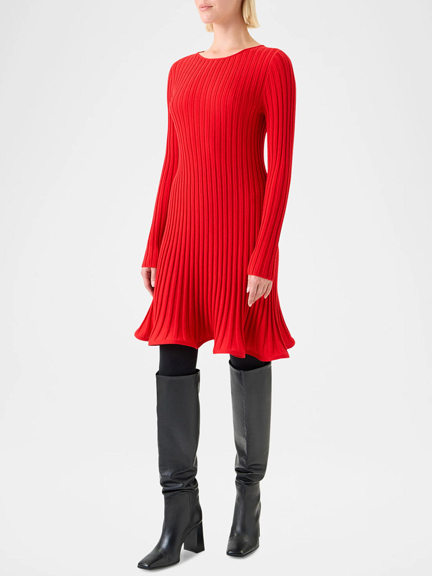 A person wears the Akris Punto Reverse Rib Fit & Flare Mini Dress in Vermillion with black tights and knee-high boots, standing against a plain light background.