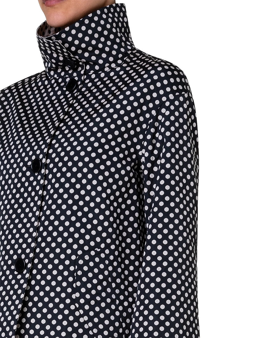 Close-up of a person wearing the Akris Punto Reversible Polka Dot Jacket in Black/Cream, featuring a dark cropped technical design with a white polka dot pattern, high collar, and large black buttons.