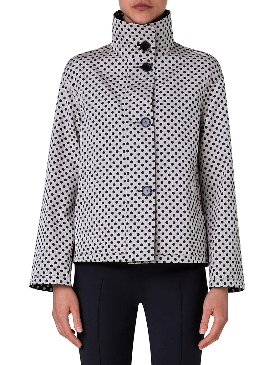A person wearing the Akris Punto Reversible Polka Dot Jacket in Black/Cream with black pants.