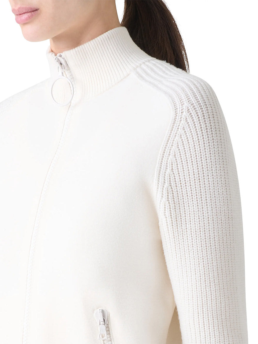 A woman wearing the Akris Punto Rib-Knit Wool Zip Cardigan in Cream, featuring ribbed knit sleeves and a stand collar, shown from shoulders to mid-torso.