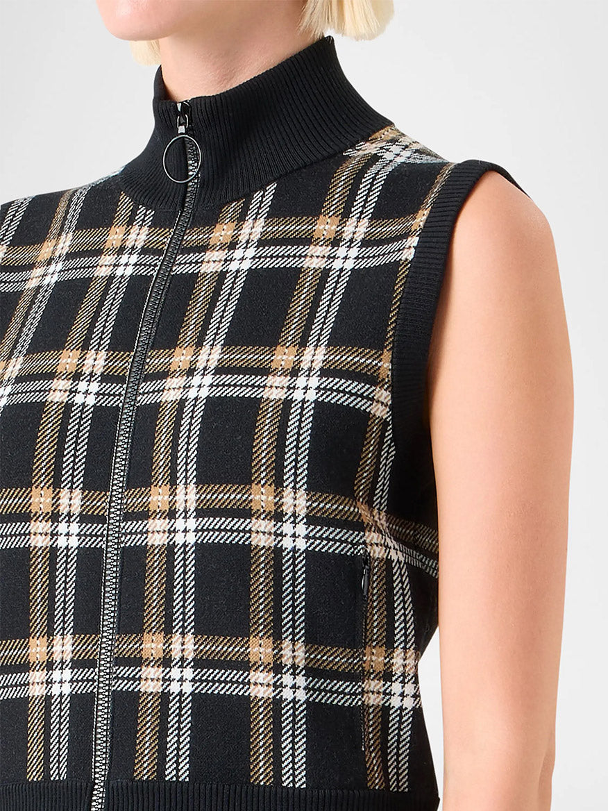 Close-up of a person wearing the Akris Punto Sleeveless Plaid Jacquard Zip Sweater in Black/Cream/Camel, featuring a high stand collar and a distinctive plaid jacquard pattern.