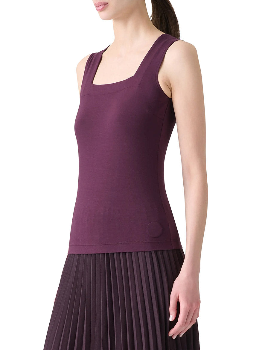 A woman wearing the Akris Punto Square-Neck Jersey Tank Top in Blackberry stands against a plain white background, paired with a matching pleated stretch skirt.
