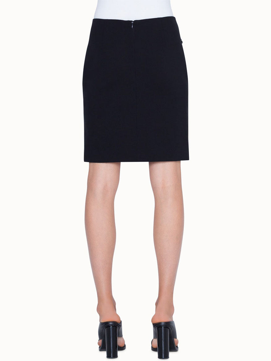 A person wearing the Akris Punto Jersey Stretch Skirt in Black with black heeled sandals is shown from the back against a plain background.