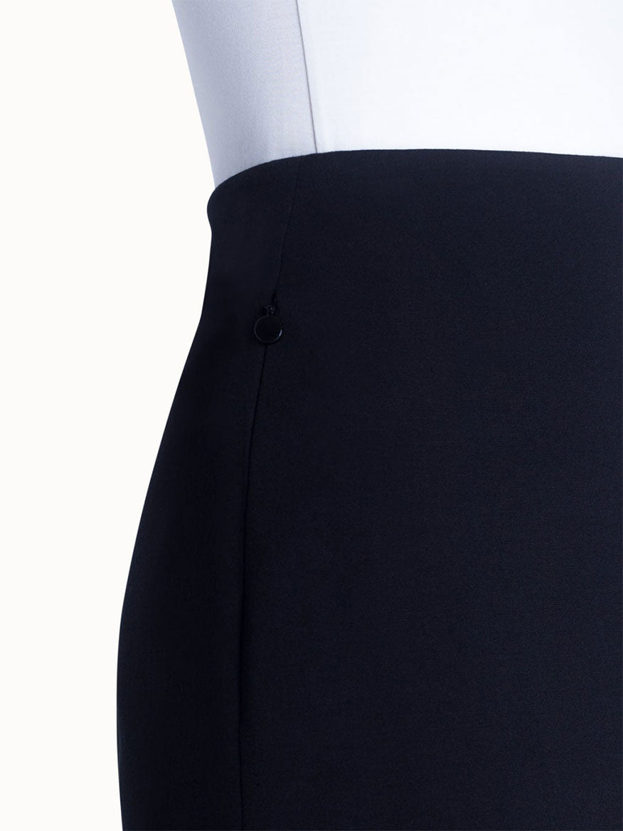 A close-up of a person in a white top tucked into the Akris Punto Jersey Stretch Skirt in Black, highlighting the high waist and left side seam with a small black ring detail.