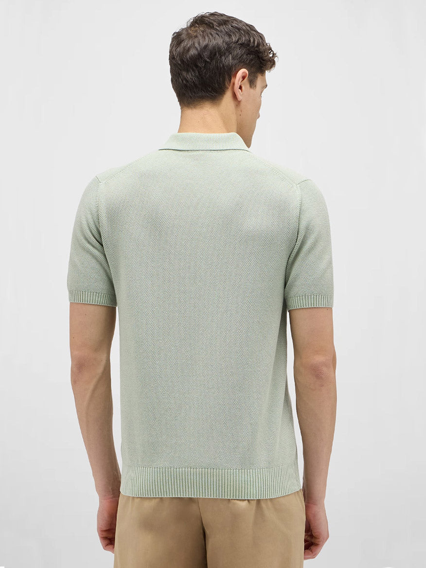 A man faces away, wearing the Maurizio Baldassari Garment Dyed Cotton Polo Honeycomb Stitch in Aqua Sky with beige pants against a plain light background.