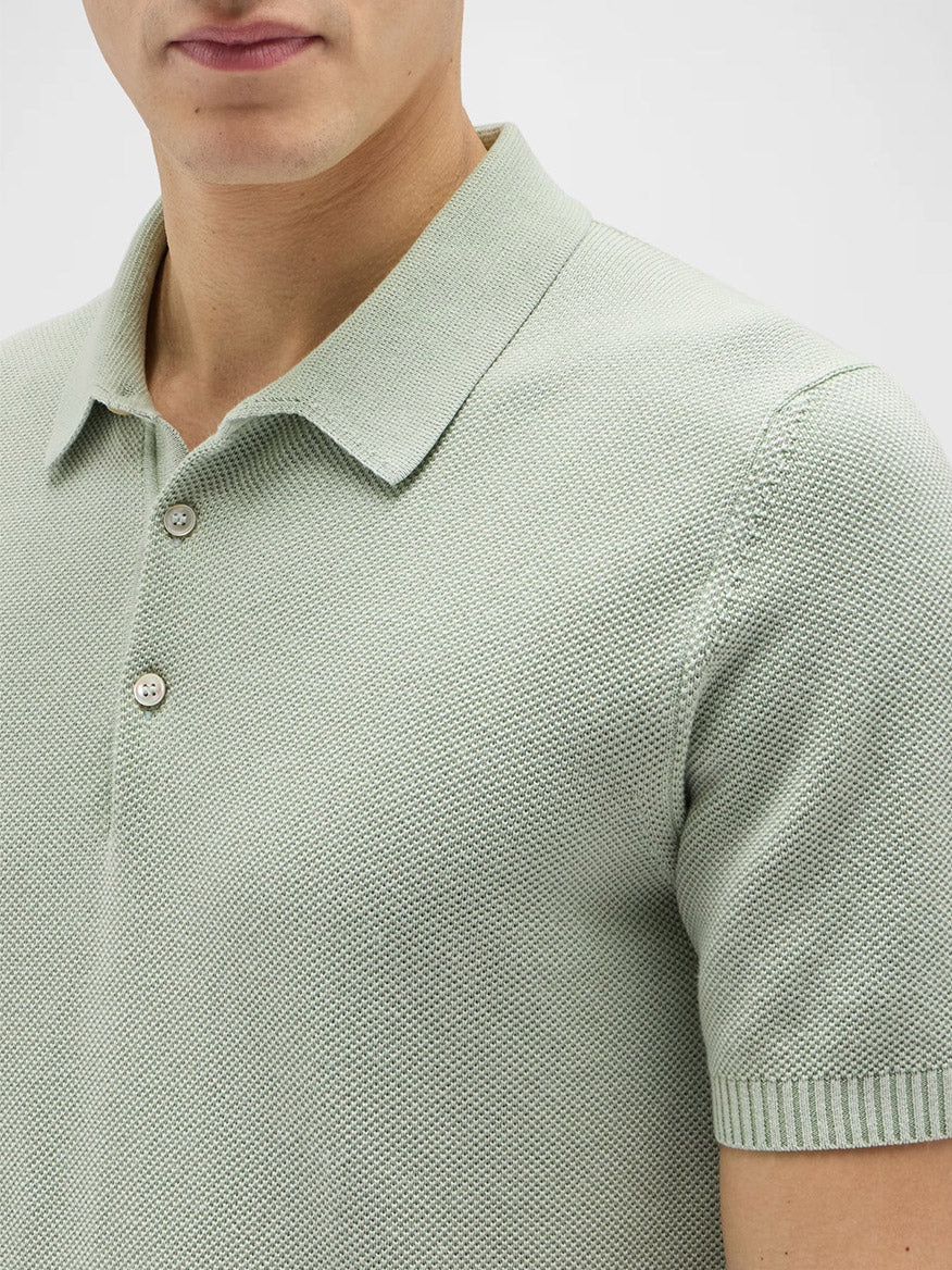 A person wearing the Maurizio Baldassari Garment Dyed Cotton Polo Honeycomb Stitch in Aqua Sky, featuring a collar and two buttons, made in Italy.