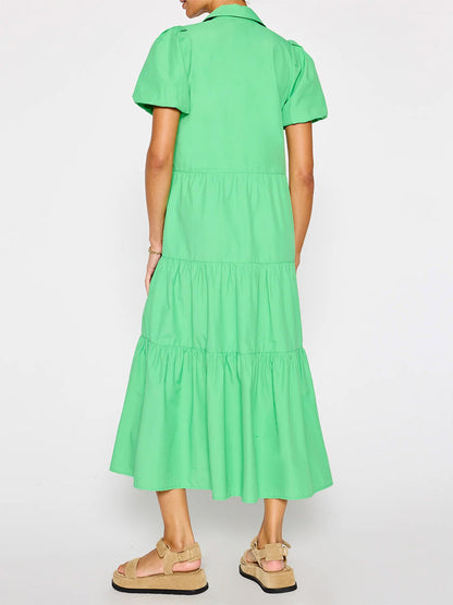 Woman from behind wearing a bright green, mid-length Brochu Walker Havana Dress in Derby Green with short sleeves and tiered skirt, paired with beige sandals.