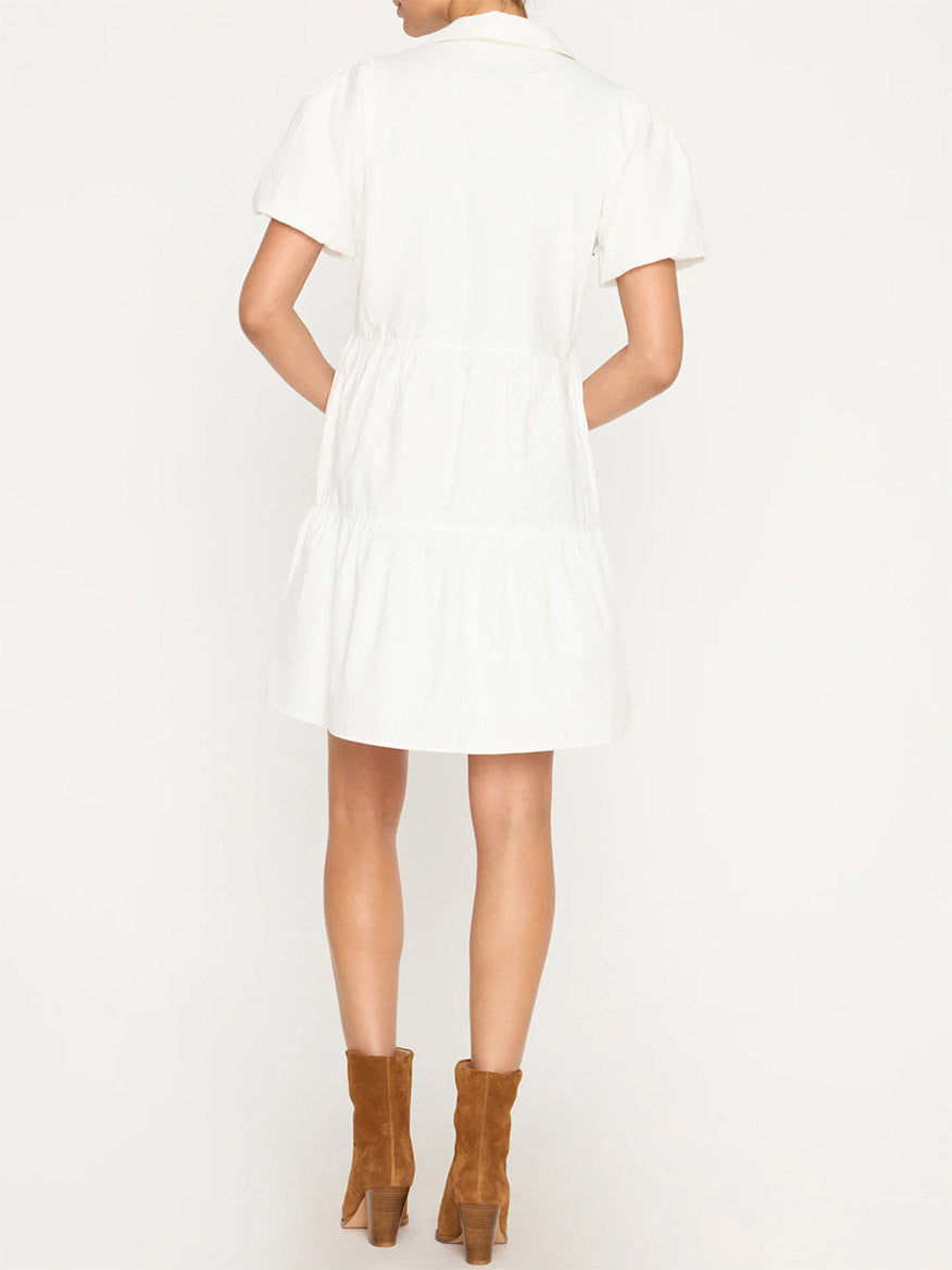 Woman standing with her back to the camera, wearing a white short-sleeved Brochu Walker Havana Mini Dress in Ivory and brown ankle boots.