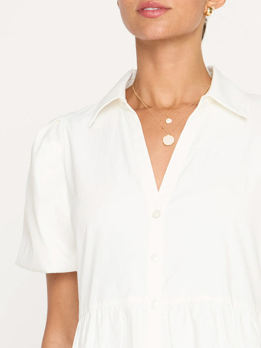 Close-up of a woman wearing a white blouse and a layered gold necklace, focusing on the area from her neck to her chest in a Brochu Walker Havana Mini Dress in Ivory.