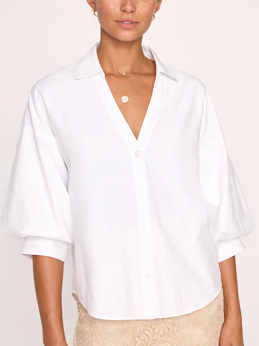 A woman wearing a Brochu Walker Kate Shirt in Salt White, an embodiment of effortless sensuality, with a v-neckline and button cuff sleeves.