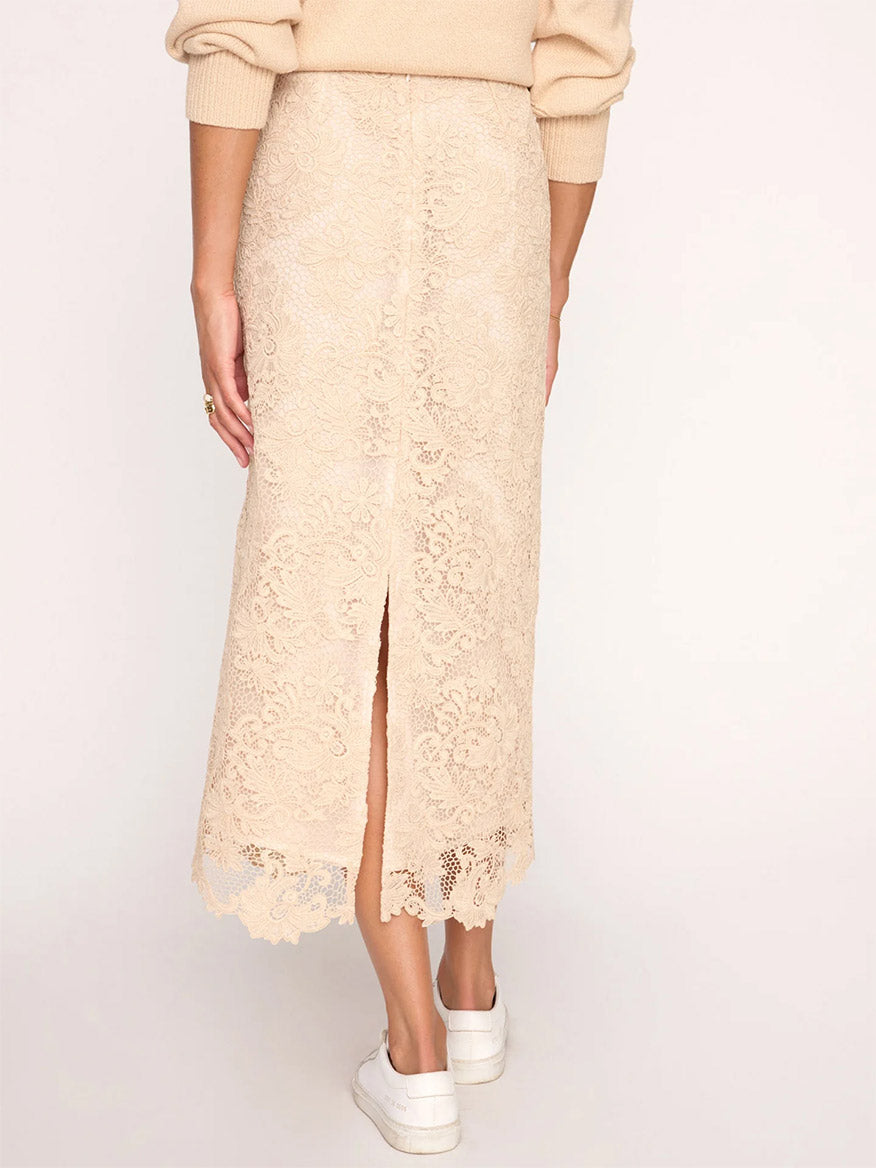 Woman wearing a Brochu Walker Mara Lace Skirt in Buff with a front slit paired with a sweater and white sneakers.