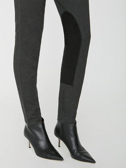 A person wearing black heeled ankle boots and the Brochu Walker Remington Riding Pant in Charcoal Melange with a contrasting black inner seam detail, featuring vegan leather panels.