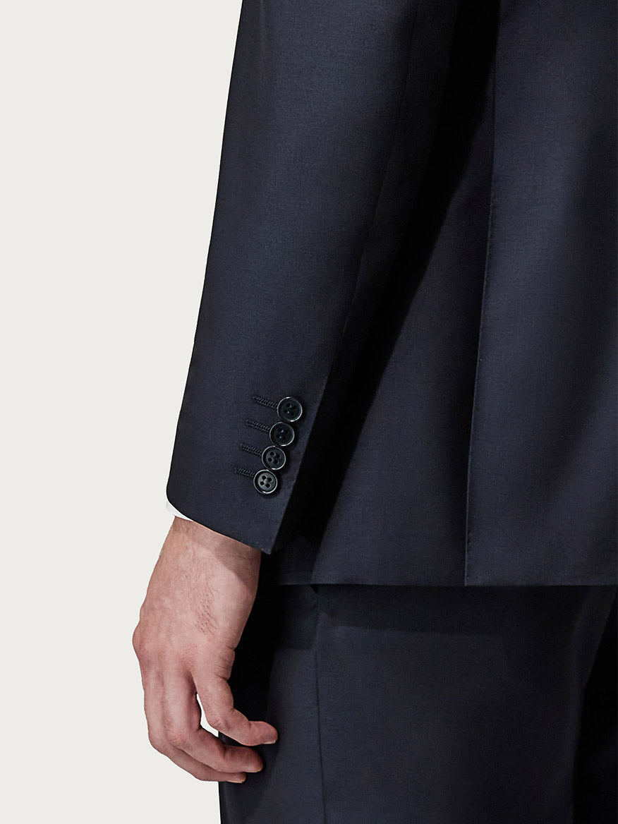 Close-up of a man's left hand and lower sleeve of a Canali Siena Contemporary Navy Blue Wool Suit with detailed buttons.