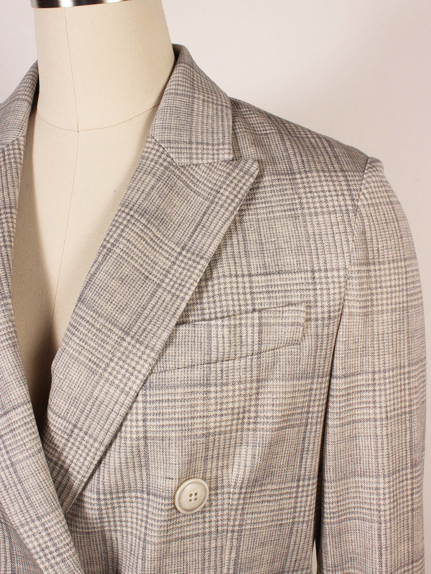 A close-up of the Circolo 1901 Prince of Wales Double-Breasted Jacket in Grey on a dress form, highlighting its beige and grey plaid pattern, peak lapels, chest pocket, and button detail.