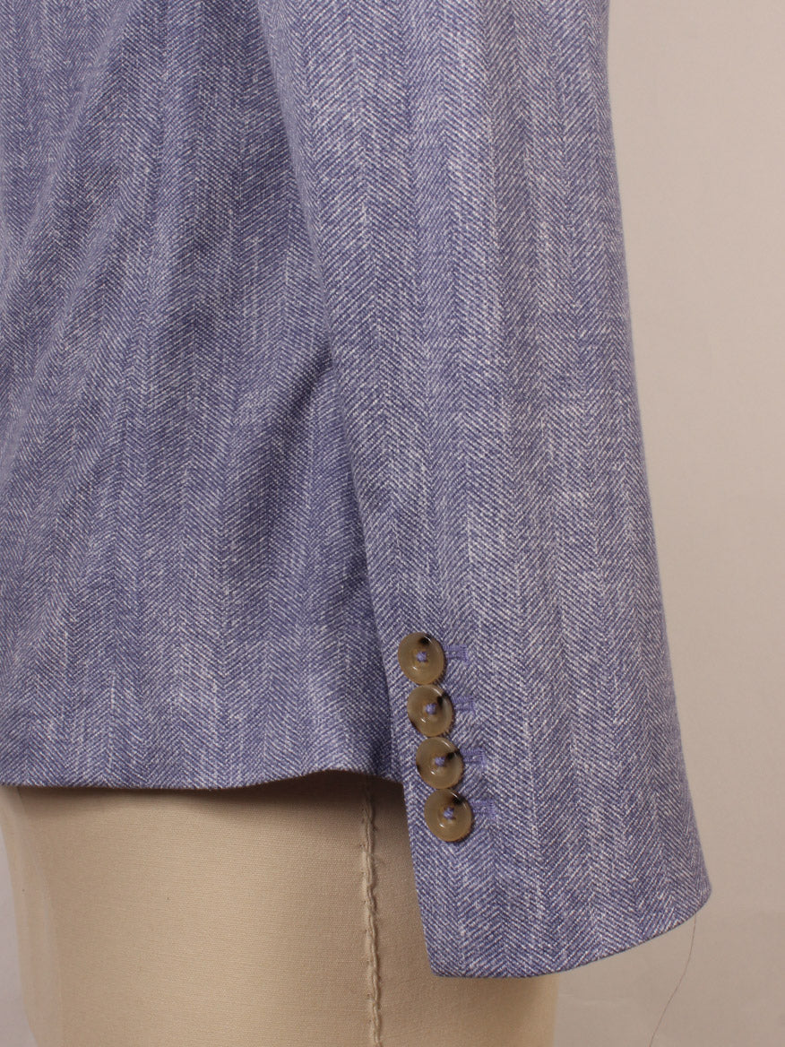 Close-up of the Circolo 1901 2-Button Slim Herringbone Jacket in Dark Sky, highlighting its sleeve with four brown buttons, displayed on a beige mannequin against a plain background.